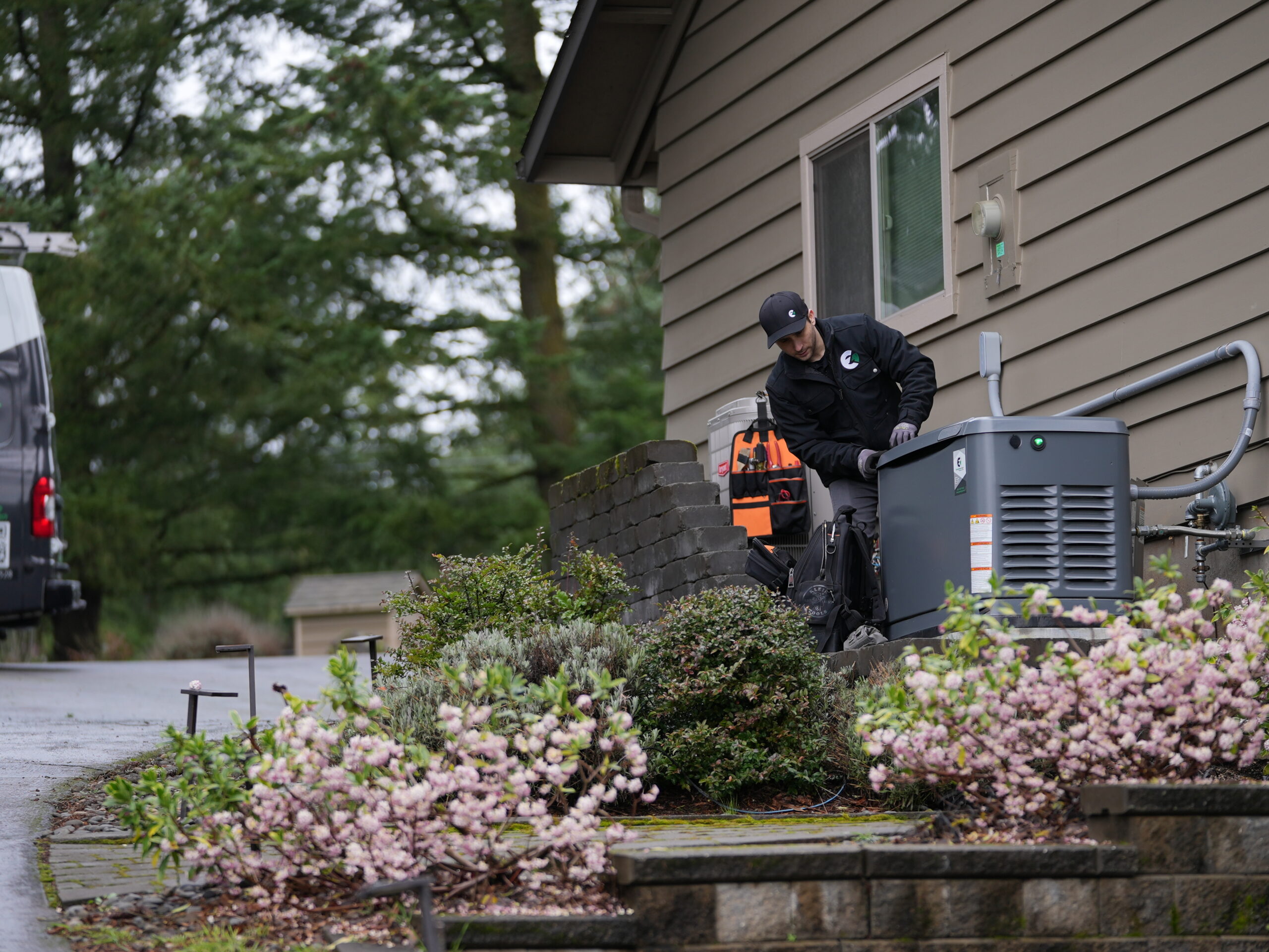 An Evergreen technician outside of a house on a spring day, next to a generator, freshly installed.